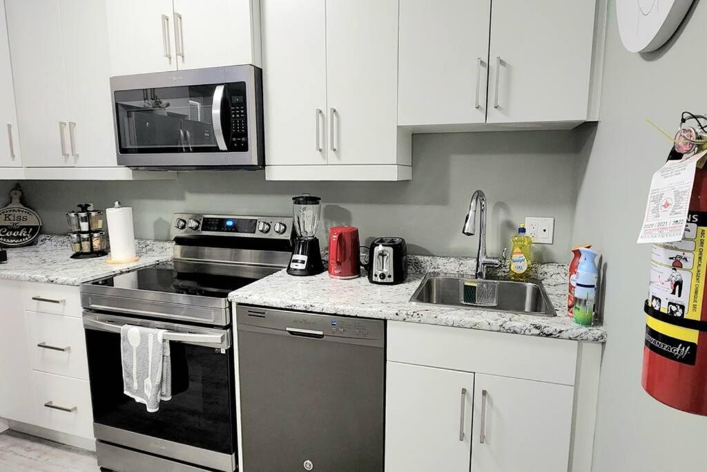 a kitchen with a stove and a sink and a microwave at QUIET & COZY MODERN SUITE CLOSE TO RCMP in Regina