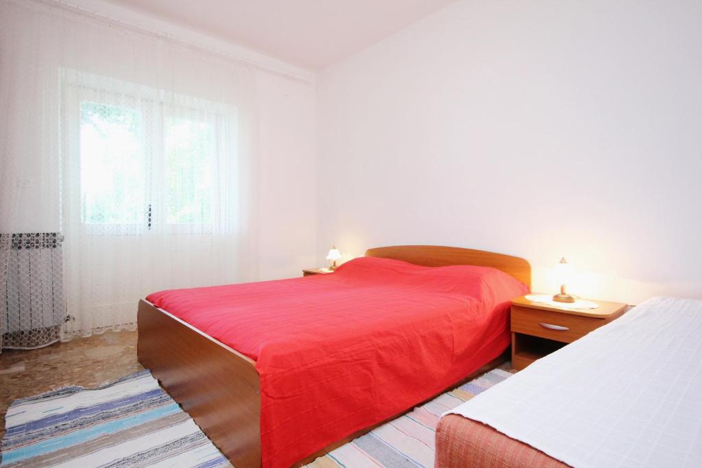 een slaapkamer met een rood bed en een raam bij Apartments by the sea Viganj, Peljesac - 633 in Viganj