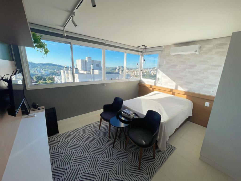 una camera da letto con un letto, due sedie e una finestra di Apartamento temático luxo Mundo do Vinho! a Bento Gonçalves