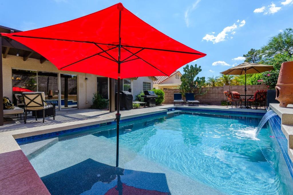 un parapluie rouge est assis dans une piscine dans l'établissement Casa De Mojave home, à Scottsdale