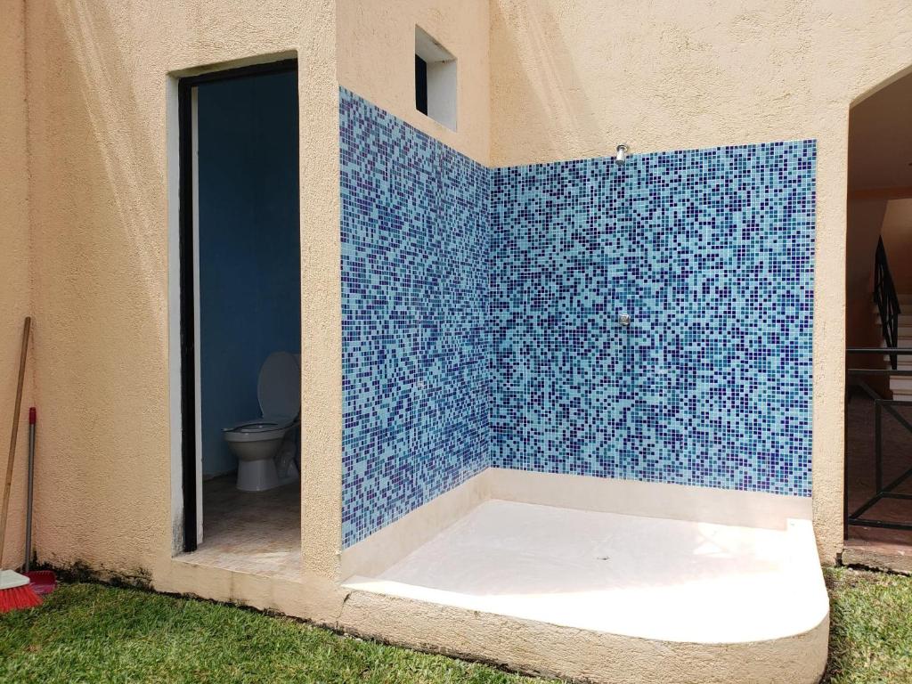 a bathroom with a blue tiled wall with a toilet at Coral Island Suites Cozumel in Cozumel