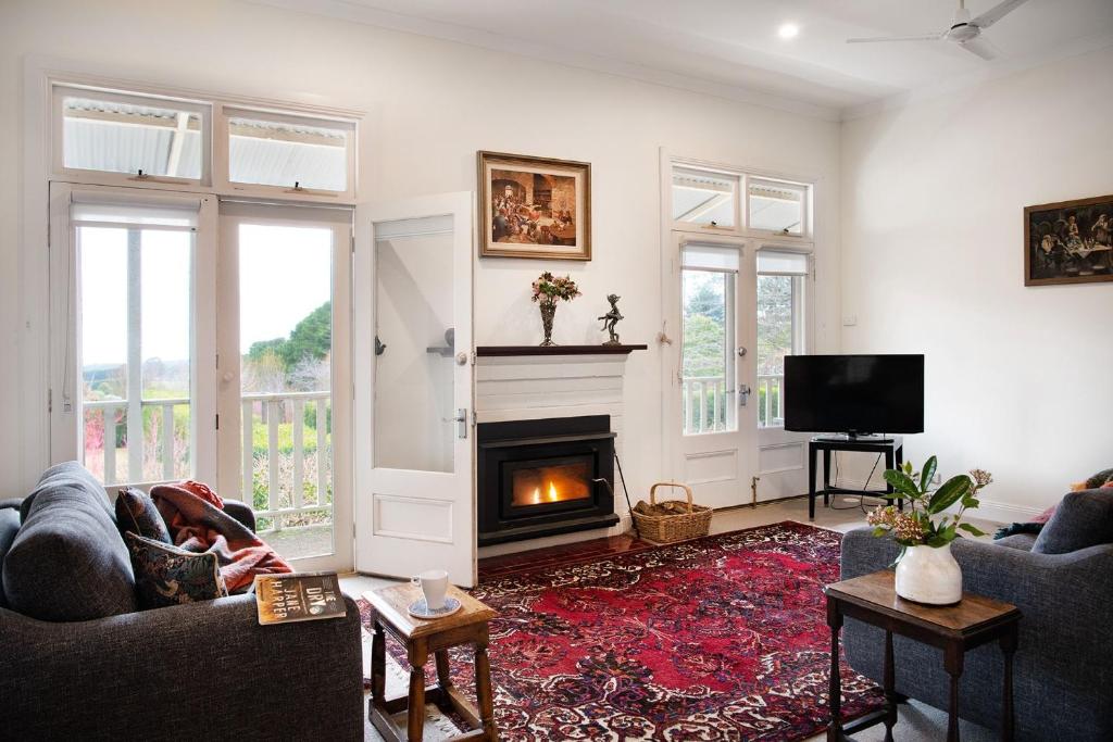a living room with a fireplace and a tv at Musk Manor Cottage in Bullarto