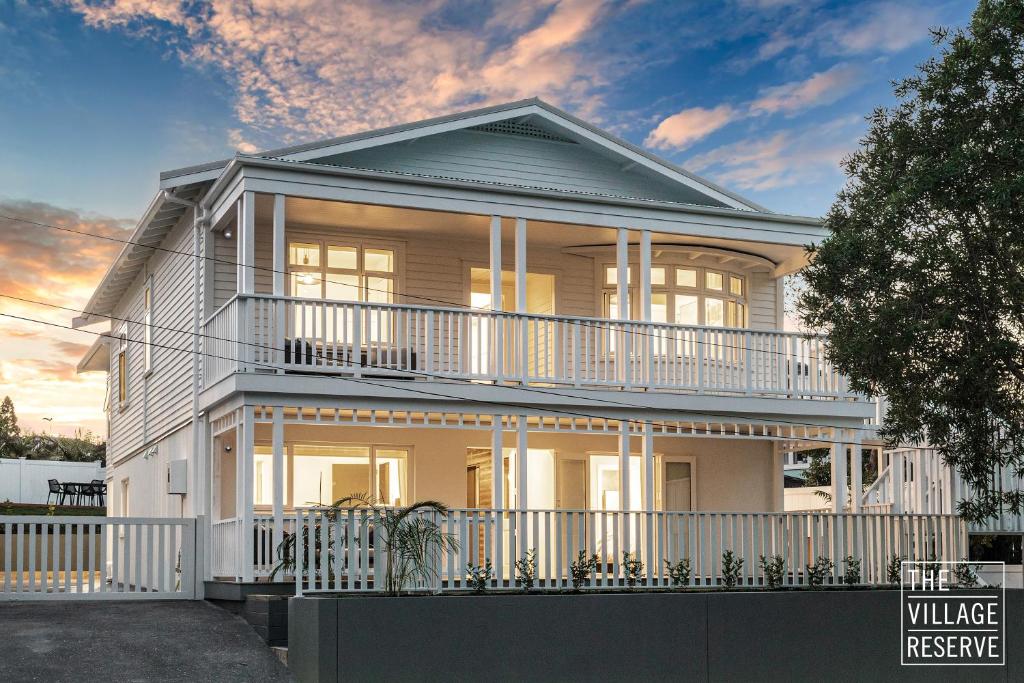 a white house with a balcony on top of it at The Village Reserve Boutique Accomodation in Auckland