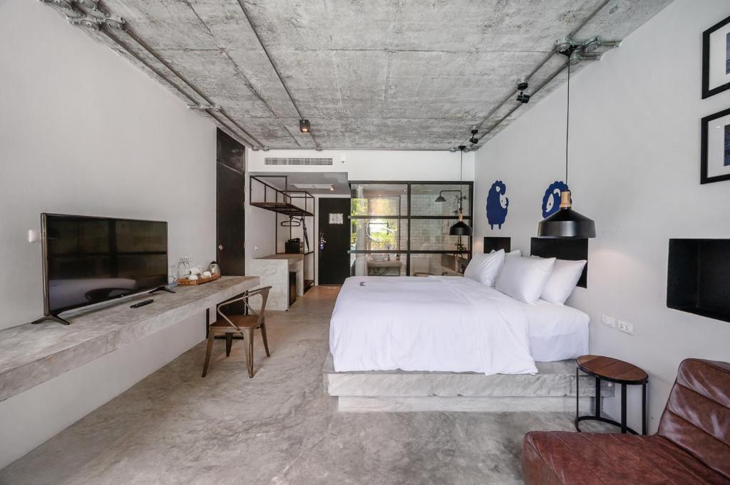 a bedroom with a large white bed and a desk at Kokotel Khao Lak Lighthouse in Khao Lak