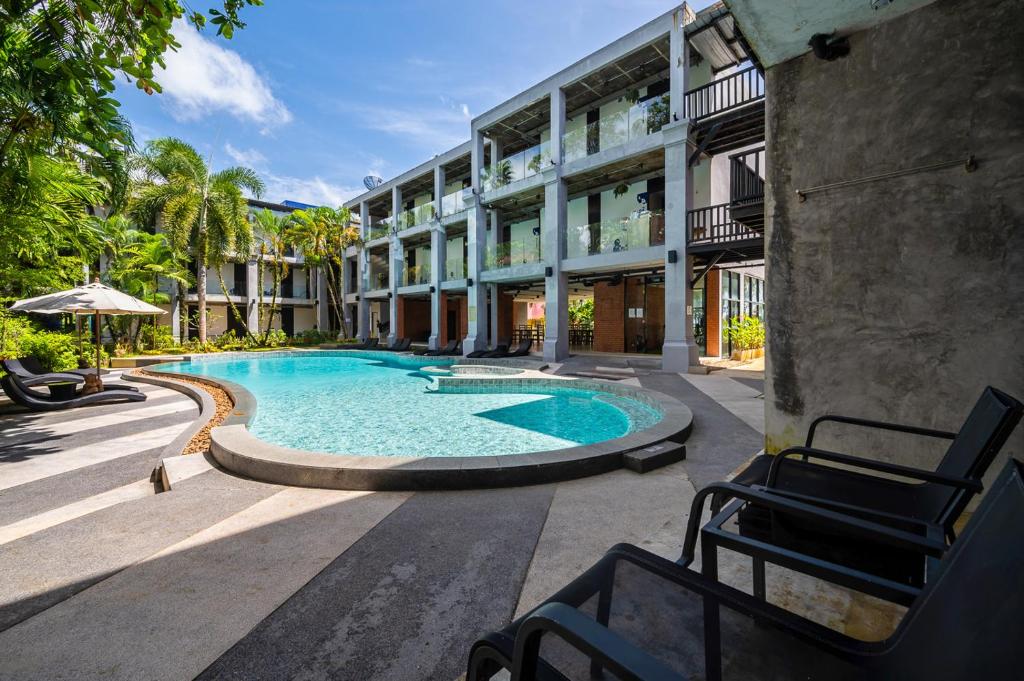 a hotel with a swimming pool in front of a building at Kokotel Khao Lak Lighthouse in Khao Lak