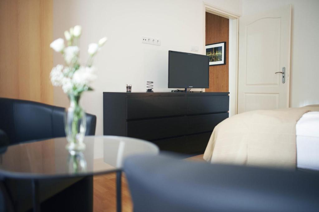 ein Wohnzimmer mit einer Blumenvase auf dem Tisch in der Unterkunft Louisa Apartment in Budapest