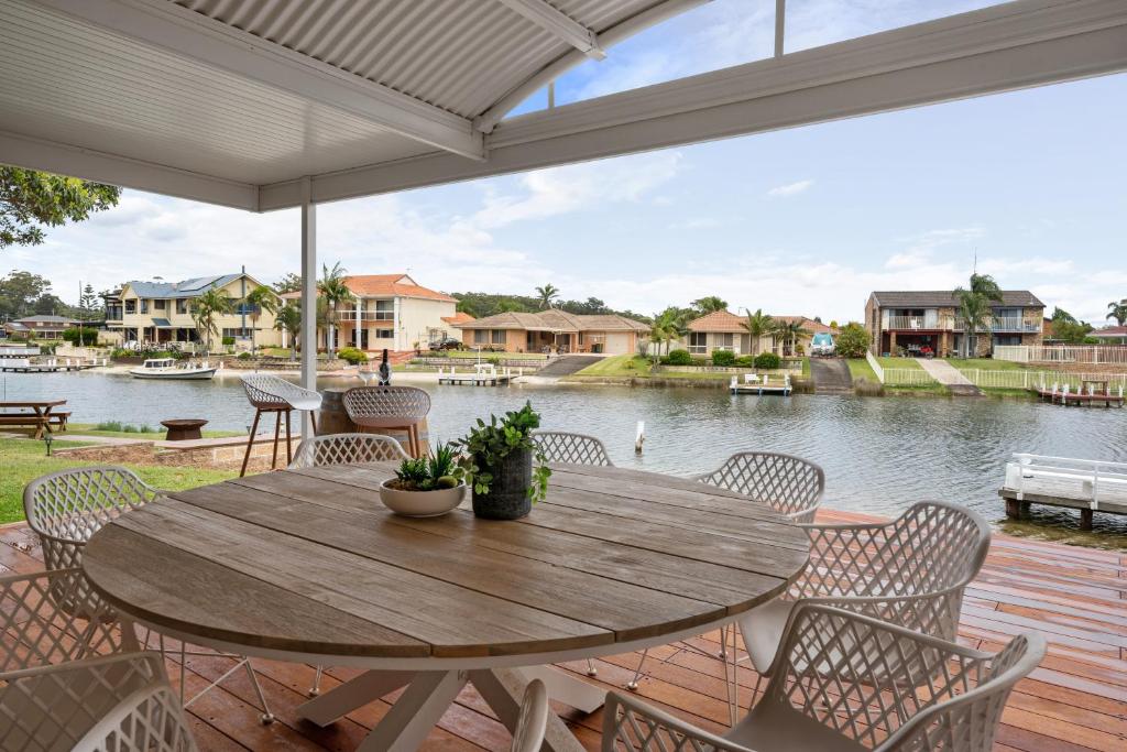 a wooden table and chairs on a deck with a view of the water at Pelican Waters in Sussex inlet