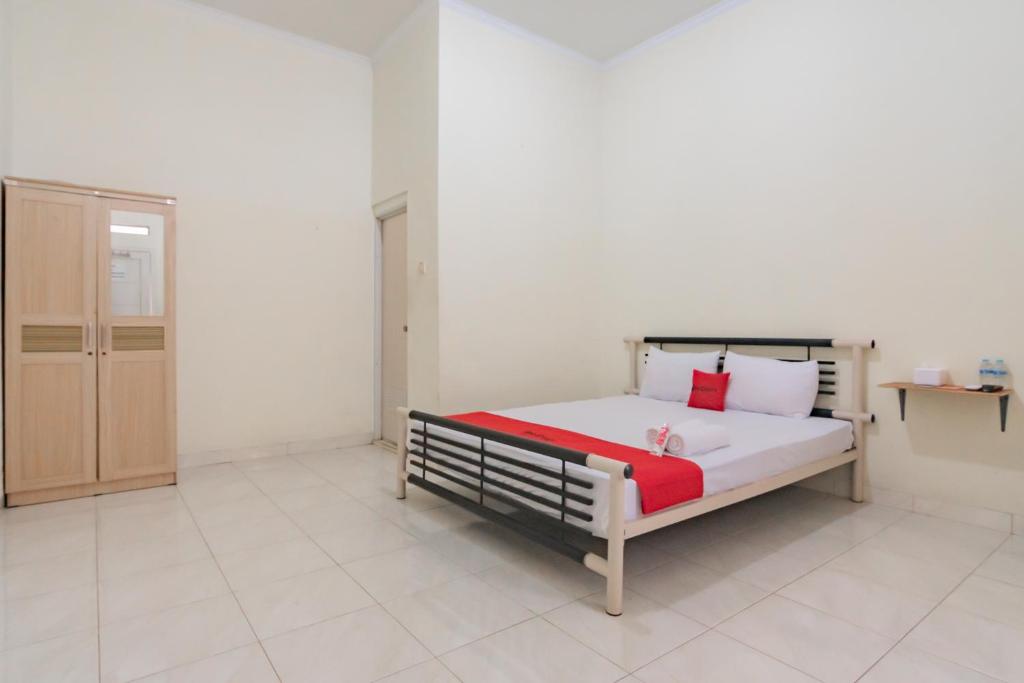 um quarto com uma cama com almofadas vermelhas e brancas em RedDoorz Syariah near Tugu Pandanwangi Cianjur 