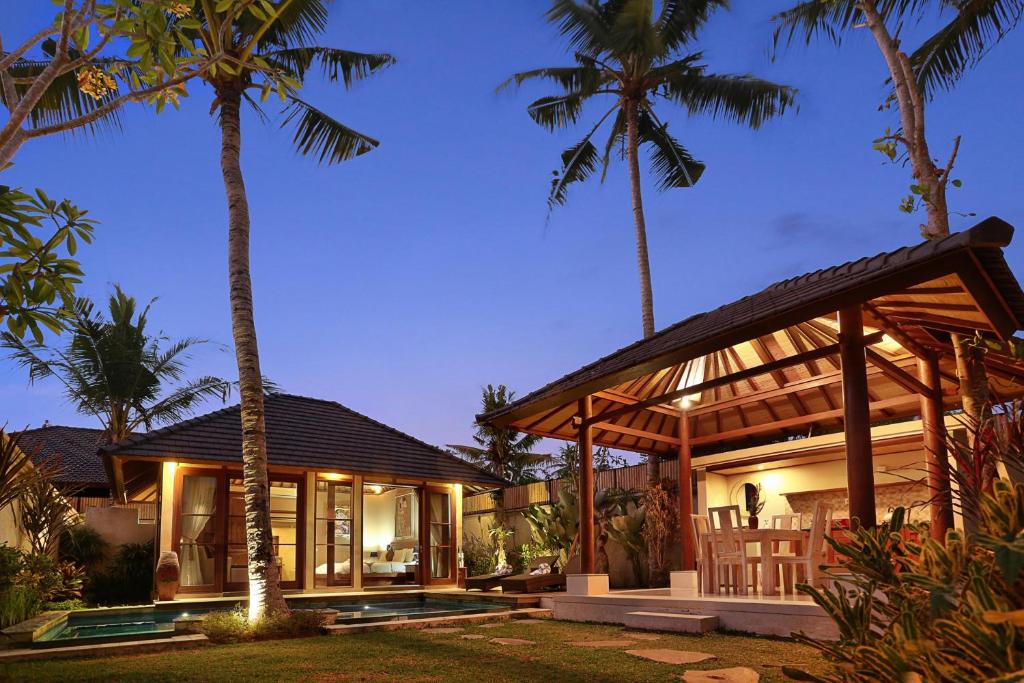 a house with palm trees in front of it at The Kampung Ubud Villa in Ubud
