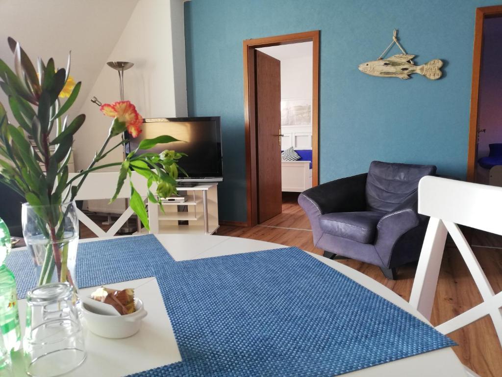 a living room with a table with a blue wall at Kajüthus Apartment 3 in Fehmarn