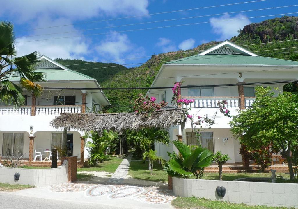 a white house with a mountain in the background at Villa Anse Possession in Baie Sainte Anne