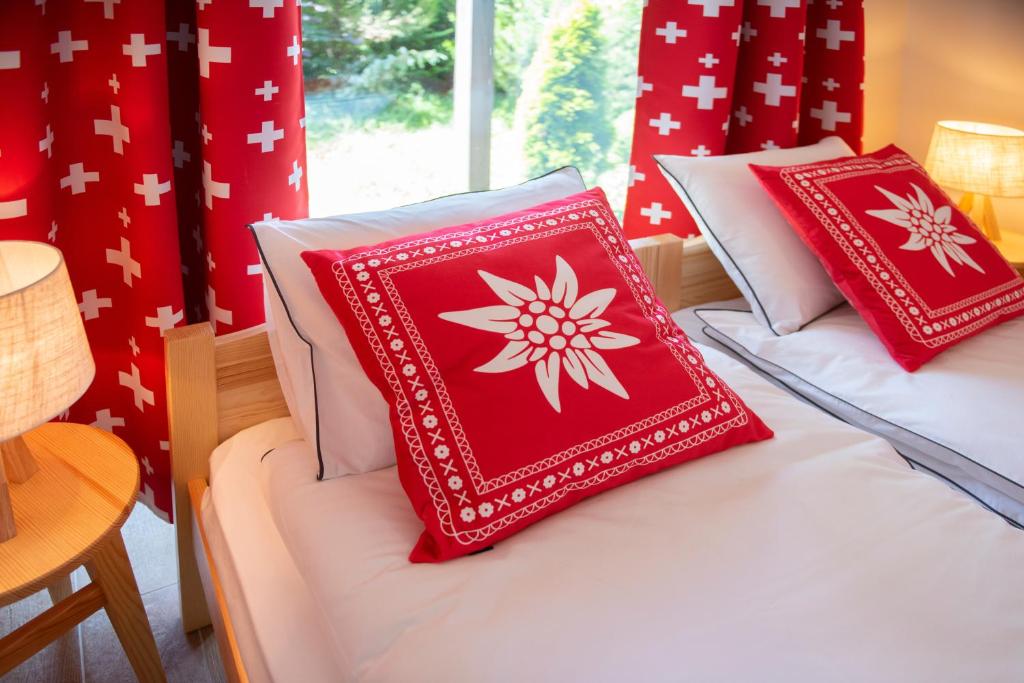 Duas camas com almofadas vermelhas e brancas em Chalet Alte Post em Schwarzsee