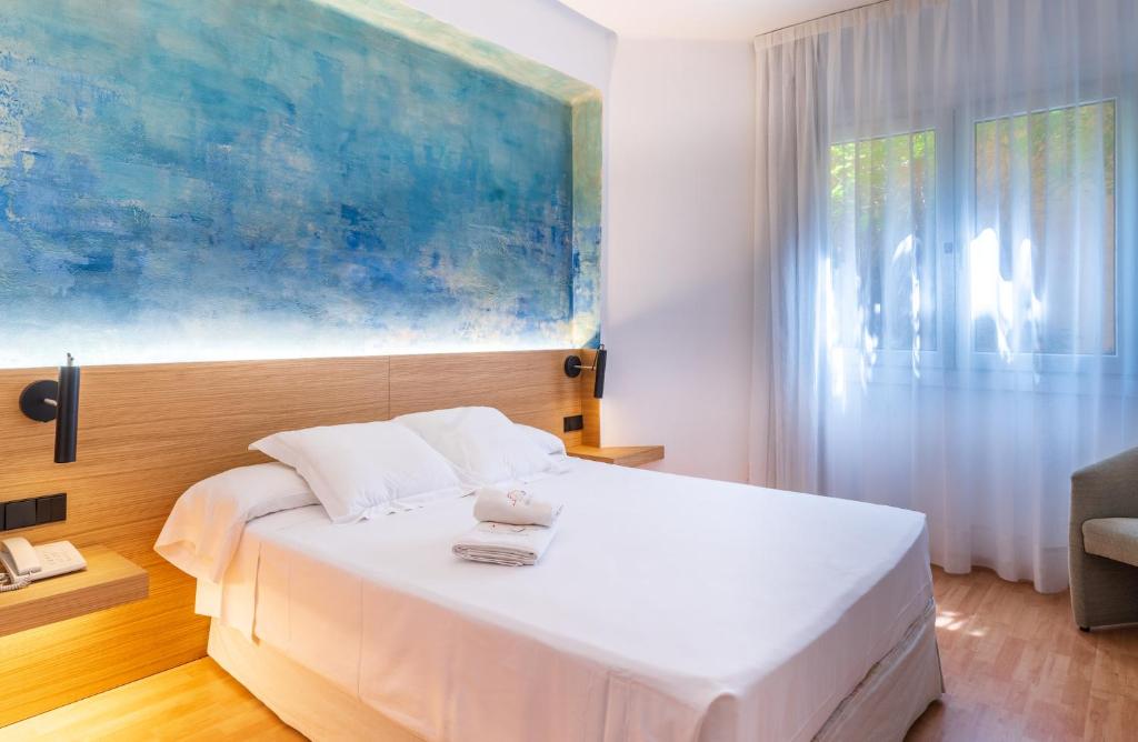 a bedroom with a white bed with a painting on the wall at Hotel Rosa & Spa Begur in Begur