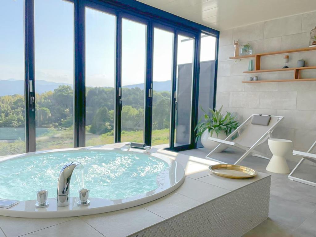 Yufuin Glamping COMOREBI في يوفو: حوض استحمام كبير في غرفة مع نوافذ
