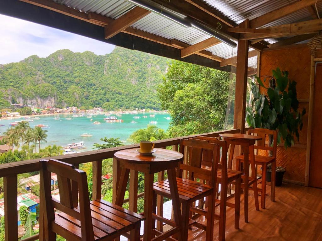 einen Balkon mit Stühlen, einem Tisch und Blick auf das Wasser in der Unterkunft BaleCabugaoCottagesRental in El Nido