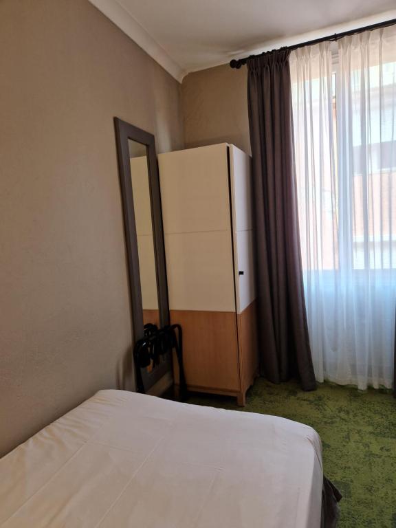 a bedroom with a white bed and a refrigerator at Hôtel La Villa Tosca in Cannes