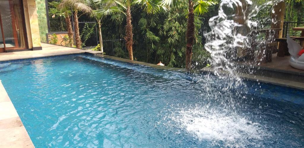 - une piscine avec une fontaine au milieu dans l'établissement Maru fortuna Villa, à Tegalalang