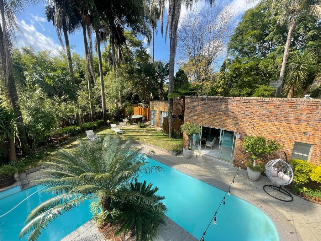 a swimming pool in front of a house with a palm tree at The Bliss Boutique in Louis Trichardt