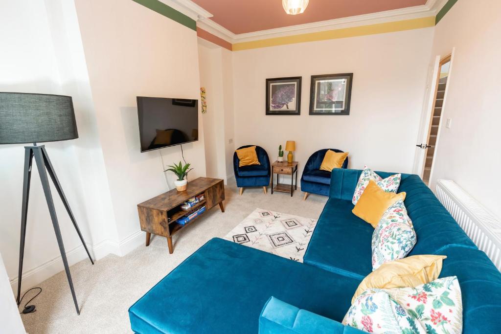 Una sala de estar con un sofá azul y un televisor. en Daffodil House, en Cockermouth