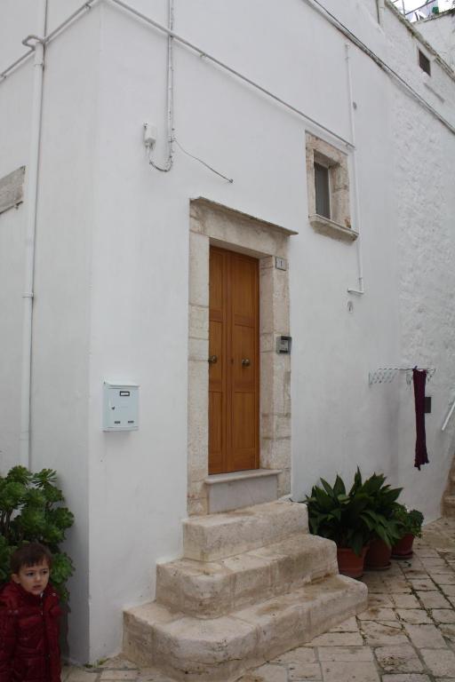 un niño pequeño parado frente a un edificio con una puerta en La casetta di Antonella, en Locorotondo