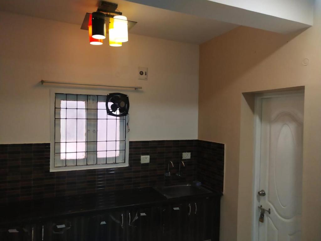 a kitchen with a sink and a window with a fan at Pearl Service Apartment in Chennai