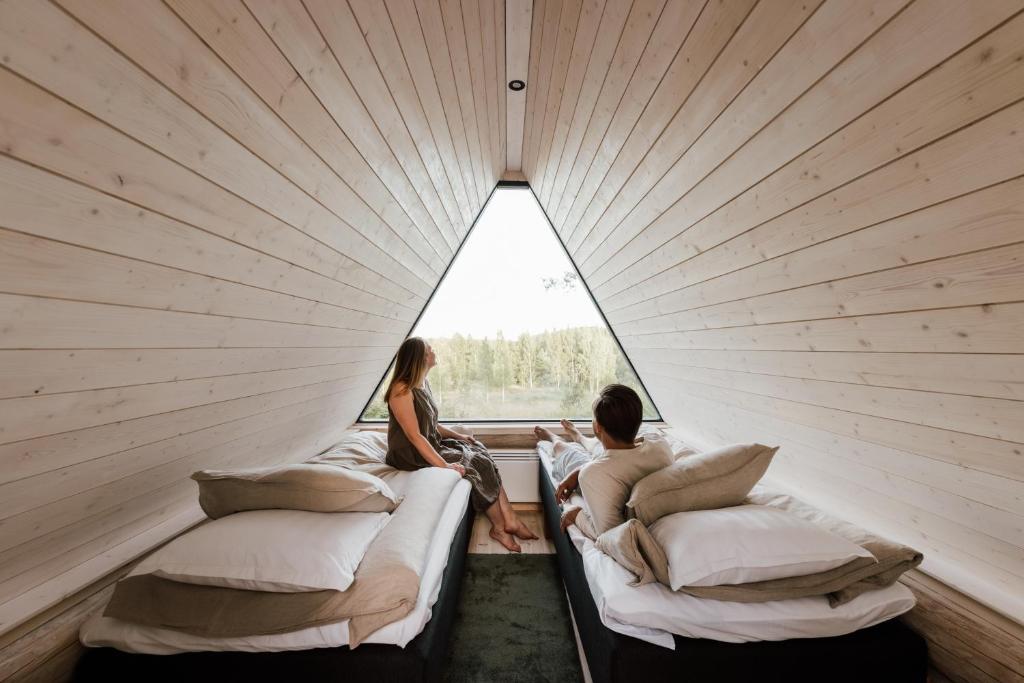 a couple sitting on beds in a room with a window at Angervo in Miehikkälä