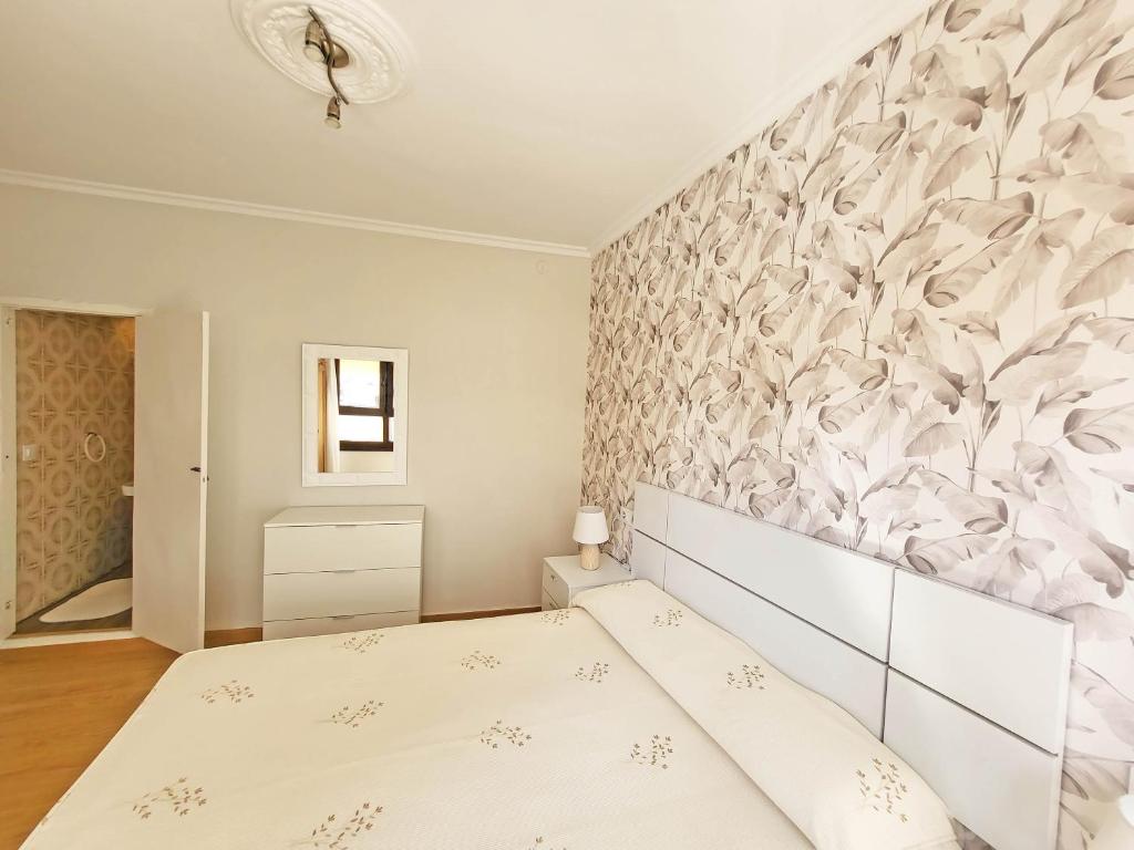 um quarto com uma cama e uma parede com flores em Apartamentos Portonovo 3000 em Portonovo