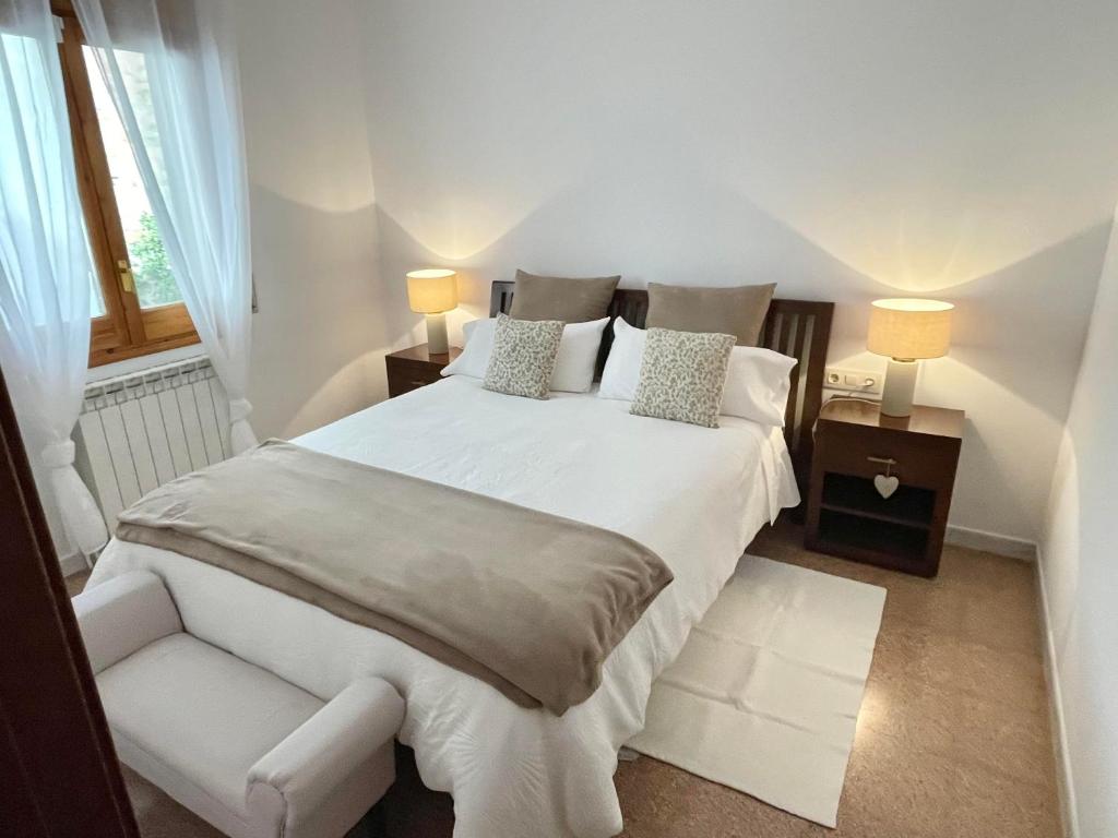 a bedroom with a large white bed and a chair at La Caseta Del Cremallera in Ribes de Freser