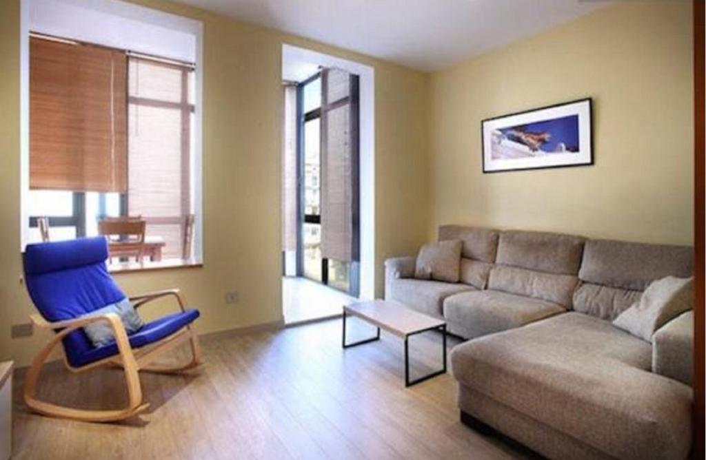 a living room with a couch and a blue chair at Actual Home Gran Via in Barcelona