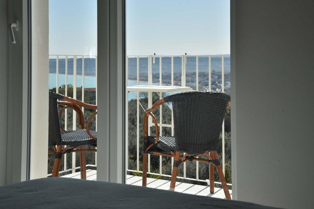 a bedroom with a bed and two chairs on a balcony at Villa Caravaggio Comfort e Relax in Rocca San Giovanni