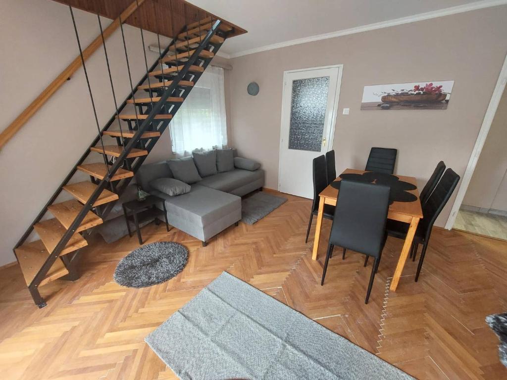 een woonkamer met een trap, een bank en een tafel bij Cinke Üdülőház in Tiszakécske