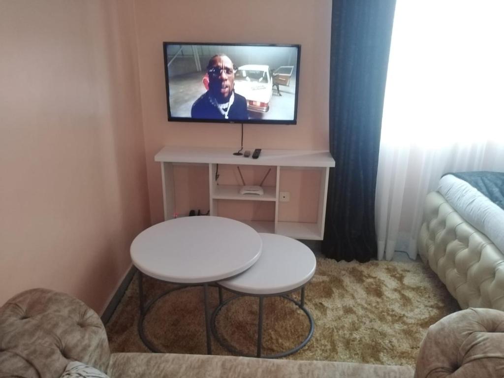 ein Wohnzimmer mit einem weißen Tisch und einem TV in der Unterkunft Executive Studio in Nakuru