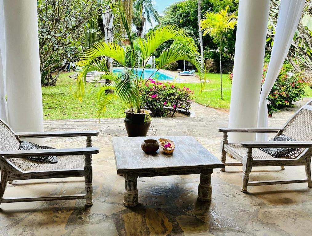 a patio with two chairs and a table and a pool at WHITE Nyumba in Malindi