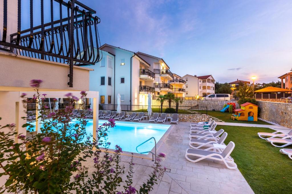una piscina con tumbonas en un patio en Cool Šilo Appartement Resort, en Šilo