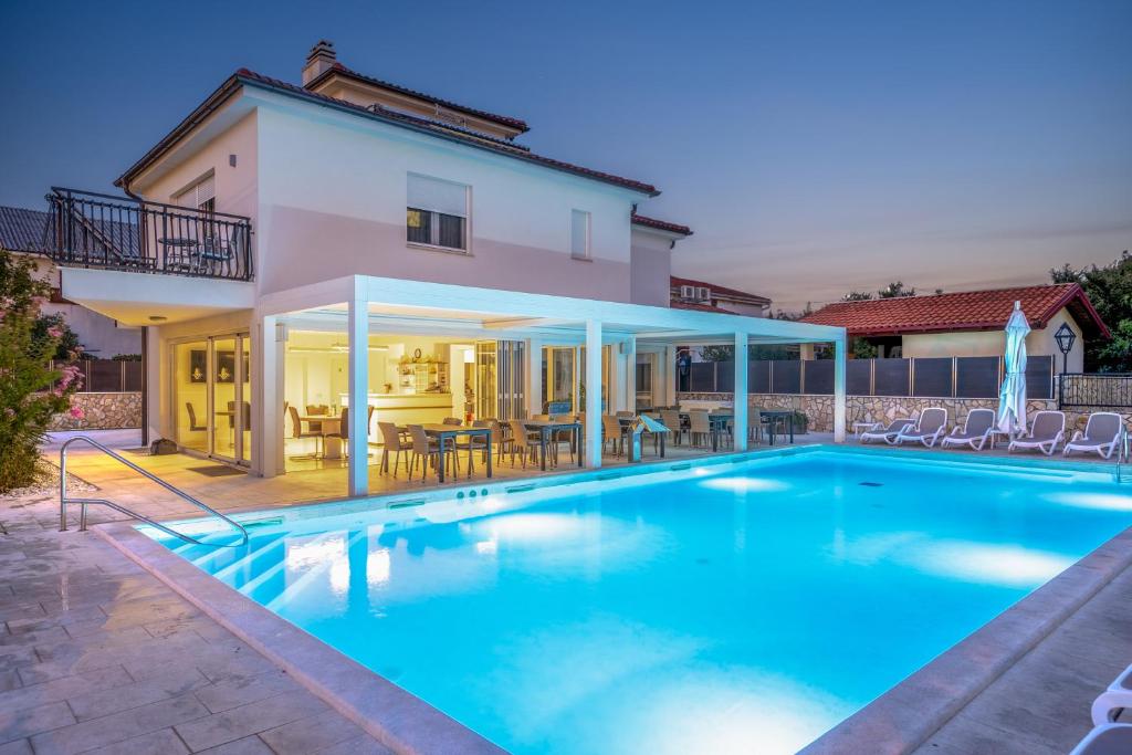 a swimming pool in front of a house at Cool Šilo Appartement Resort in Šilo
