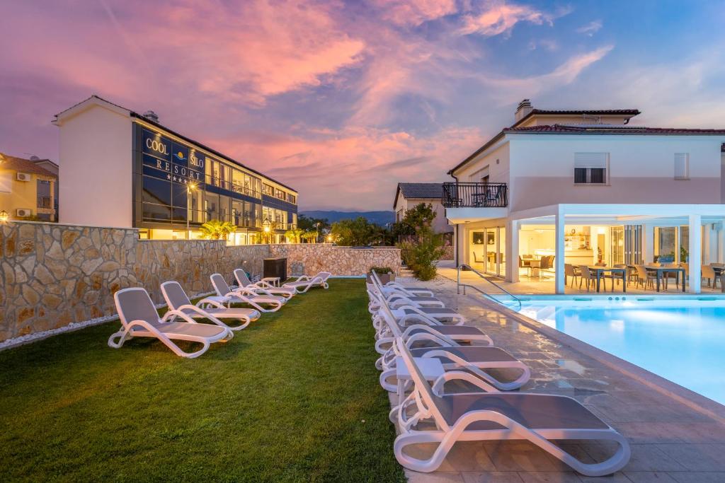 a row of lounge chairs next to a swimming pool at Cool Šilo Appartement Resort in Šilo