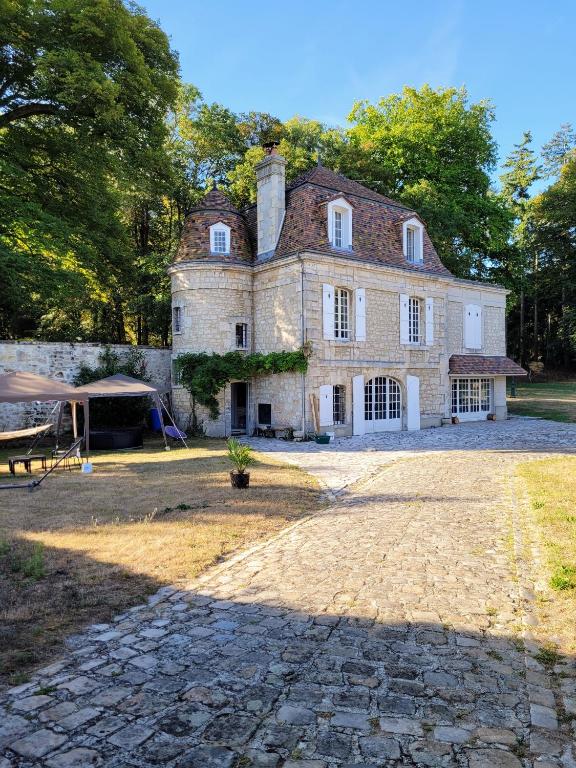 une ancienne maison en pierre avec une tente en face de celle-ci dans l'établissement LE MANOIR PARADI, à Presles-et-Thierny
