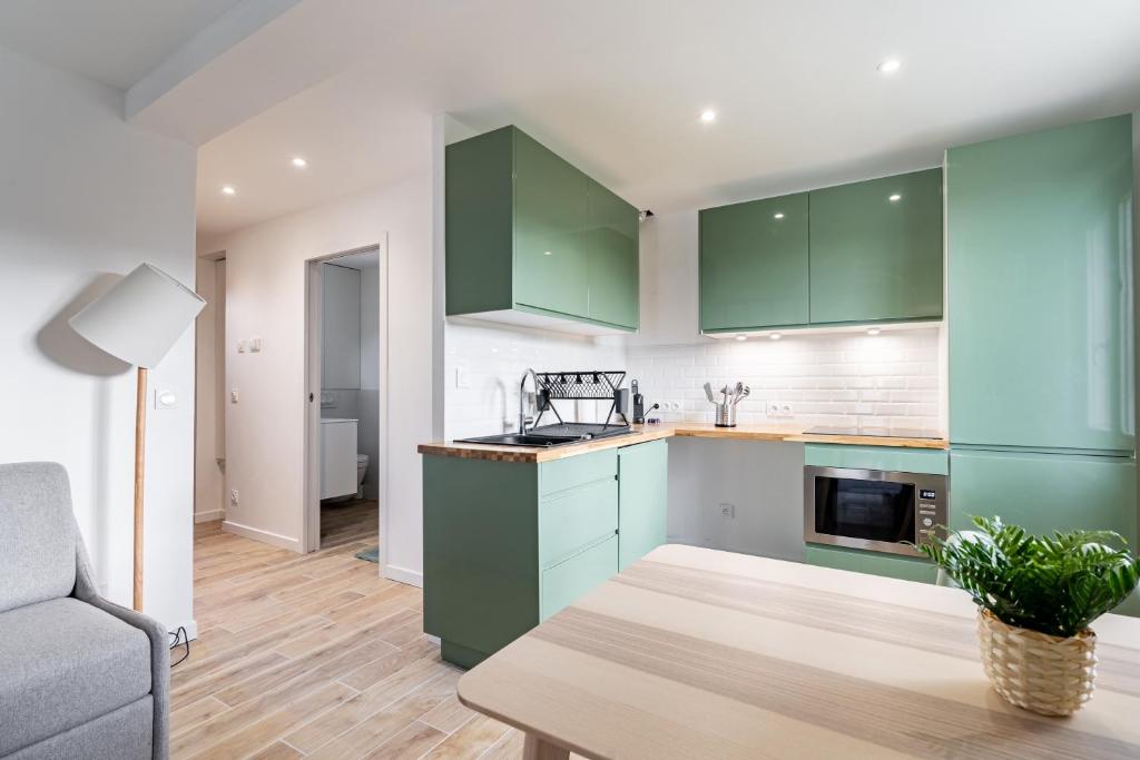 a kitchen with green cabinets and a table at Welcome perche ! Appartements 3 étoiles à NOGENT le Rotrou in Nogent-le-Rotrou