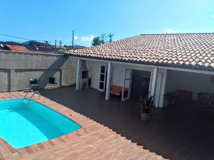 una casa con piscina frente a ella en Pousada da Sú en Bertioga