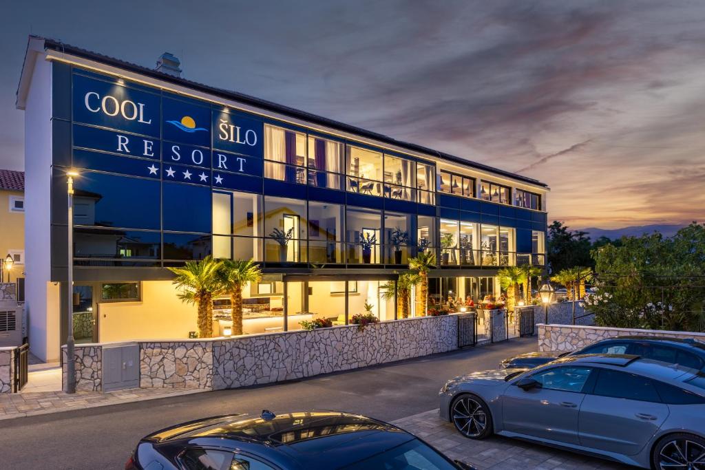 two cars parked in front of a hotel at Cool Šilo Appartement Resort in Šilo