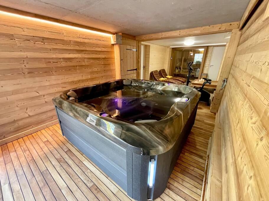 a large tub in a room with a wooden floor at Chalet Kelly, centre ville / Jacuzzi / Sauna in Gérardmer