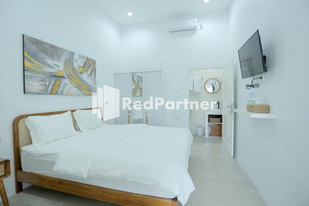 a white bedroom with a white bed and a tv at Pringgading Surf Camp Mitra RedDoorz in Bengkulu