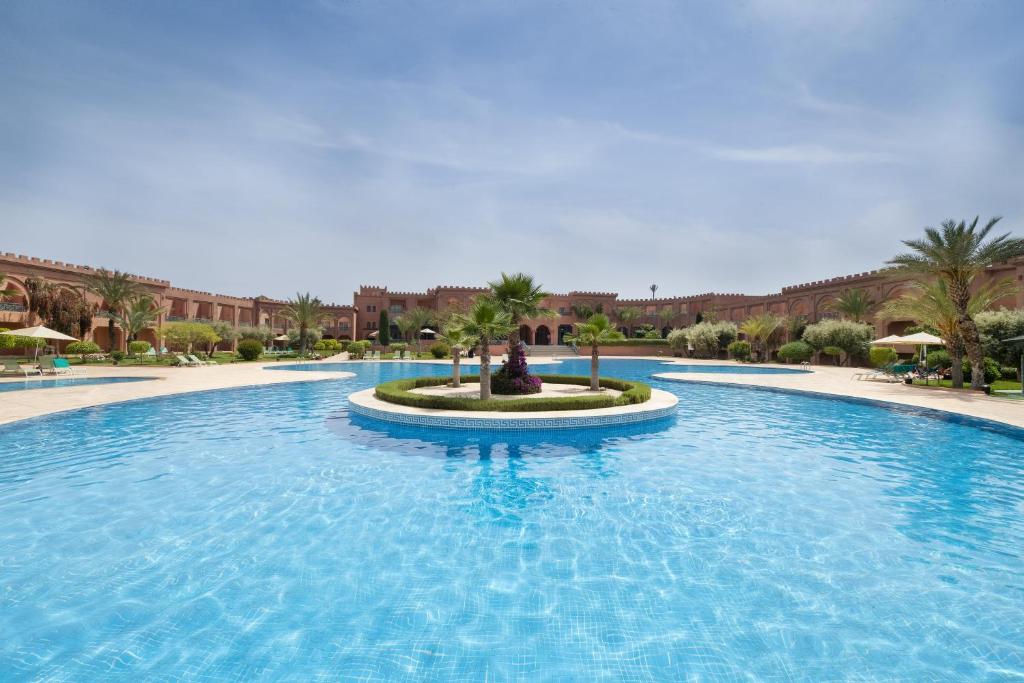 - une grande piscine dans un complexe avec des palmiers dans l'établissement Grand Mogador Agdal & Spa, à Marrakech