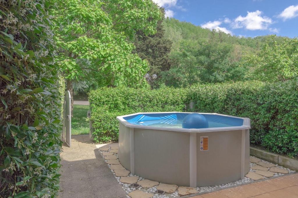einen Whirlpool in einem Garten neben einer Hecke in der Unterkunft Villetta Bosco in Corsanico-Bargecchia