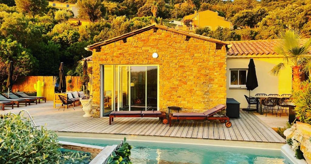 ein kleines Haus mit einer Terrasse und einem Pool in der Unterkunft VILLA PERLA SAINT-TROPEZ CAVALAIRE sur MER, 3-5 chambres, vue mer, piscine chauffée avril à octobre in Cavalaire-sur-Mer