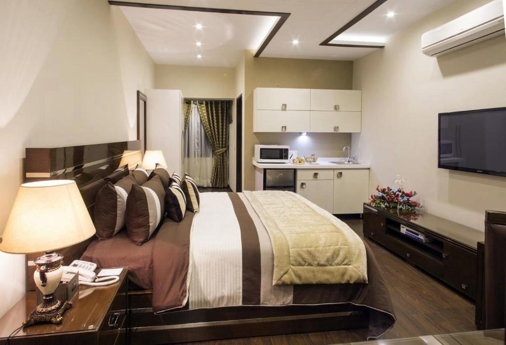 a bedroom with a large bed and a kitchen at Royaute Luxury Suites and Hotel Gulberg Lahore in Lahore