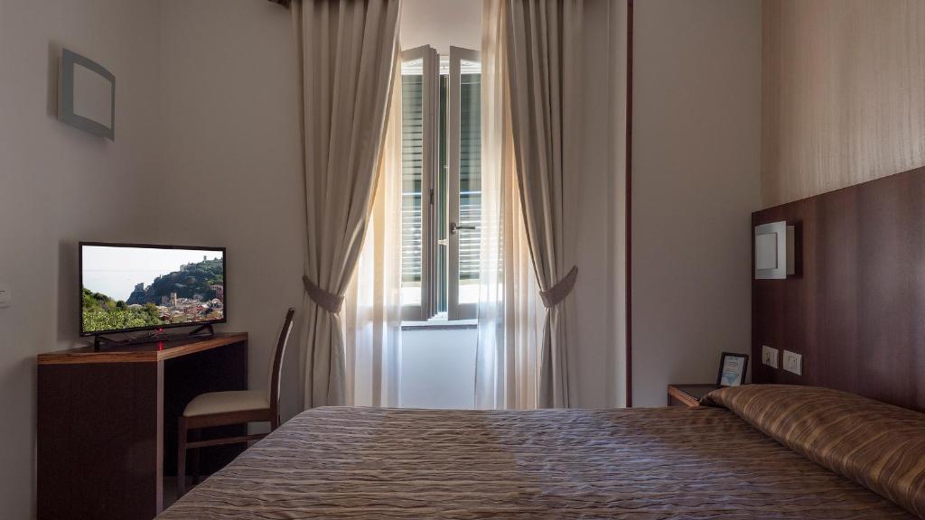 a bedroom with a bed and a television and a window at Hotel Margherita in Monterosso al Mare