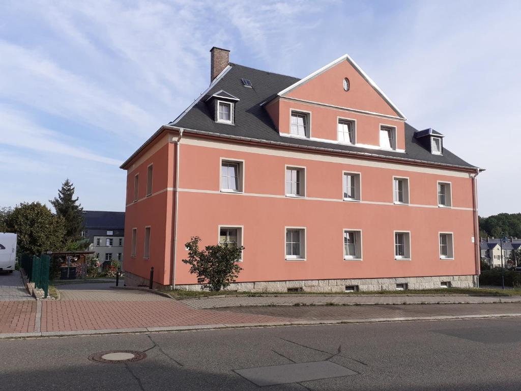 ein großes orangefarbenes Gebäude mit schwarzem Dach in der Unterkunft Ferienwohnung - August-Bebel-Str. 19 in Oelsnitz