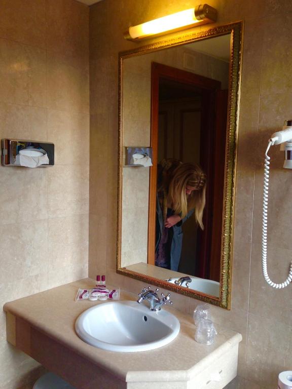 a woman taking a picture in a bathroom mirror at Hotel Amadeus in Venice