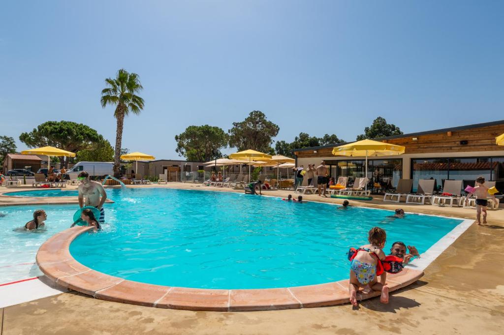 una piscina en un complejo con gente dentro en Camping maeva Escapades Les Cottages de Perpignan, en Perpiñán